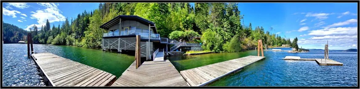 Lakeside house with docks and forest backdrop.