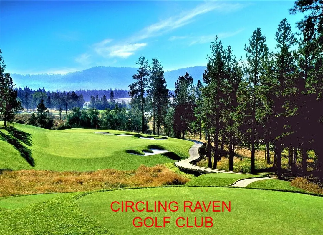 Golf course surrounded by trees and mountains.