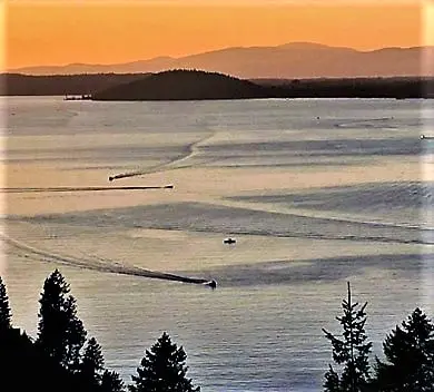Sunset over calm lake with distant hills.